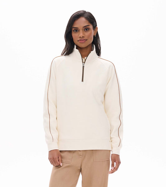 Front view of an ivory 1/4 zip top with stand collar and contrast piping down the sleeves