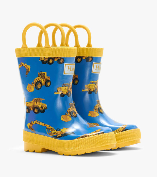 Pair of blue kids rain boots with yellow handles and trim, printed with yellow construction trucks