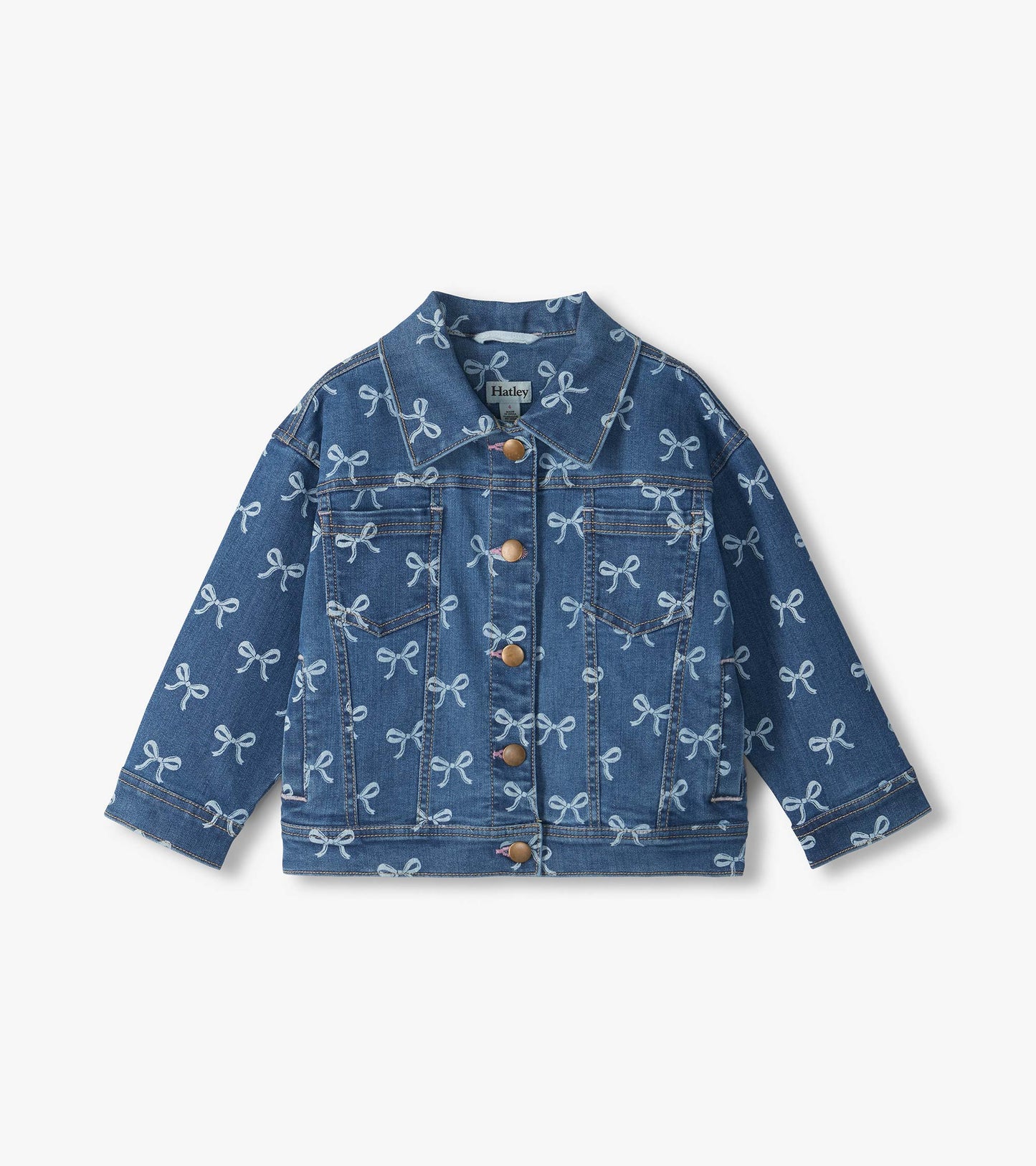 Front view of blue slouchy denim jacket with allover white bow print, chest pockets, and button front