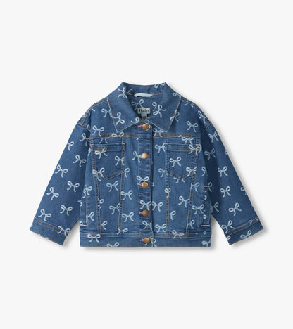 Front view of blue slouchy denim jacket with allover white bow print, chest pockets, and button front