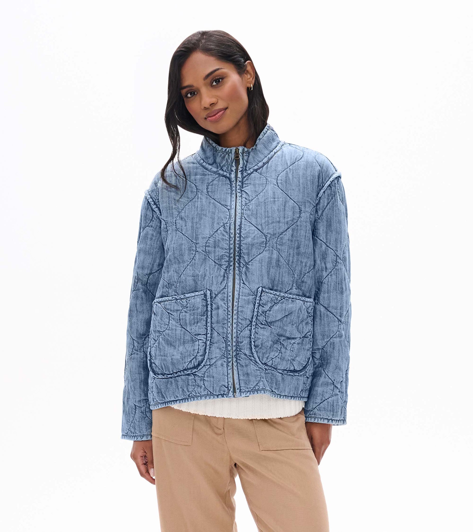 Model wearing blue acid rinse quilted jacket with stand collar, front zip, and large front patch pockets