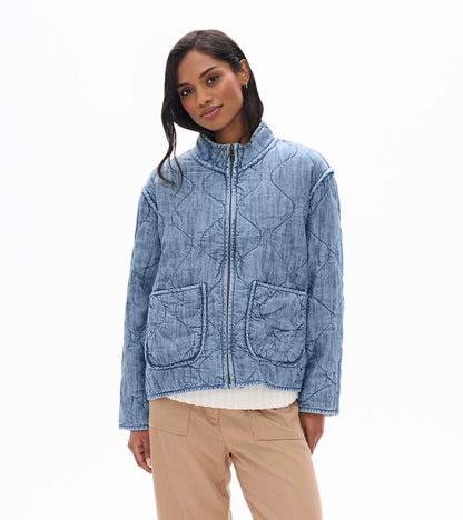 Model wearing blue acid rinse quilted jacket with stand collar, front zip, and large front patch pockets