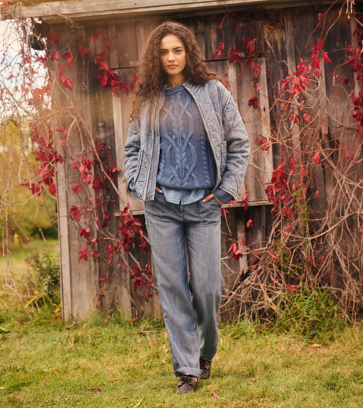Women's blue acid-rinse quilted jacket worn open with a blue cable-knit sweater, front view