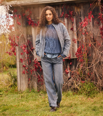 Women's blue acid-rinse quilted jacket worn open with a blue cable-knit sweater, front view