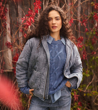 Close-up of the stellar blue cable knit sweater under a faded blue jacket and collared shirt