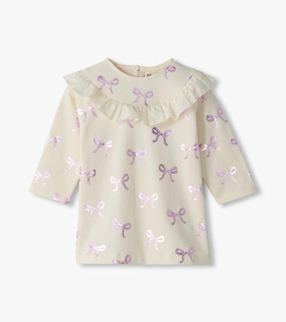Front view of infant cream ruffle dress with long sleeves and pink foil bow print