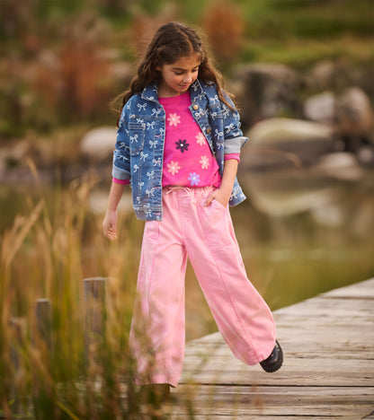 Girl modeling flamingo pink wide leg jeans with a pink top and denim jacket outdoors