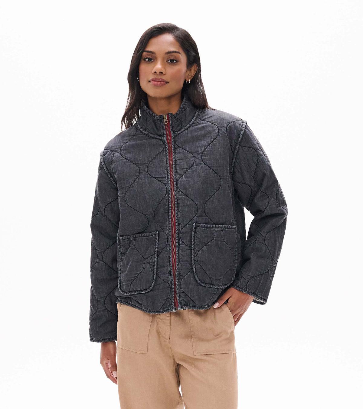 Model wearing black quilted jacket front view with stand collar, burgundy zip, and two front pockets