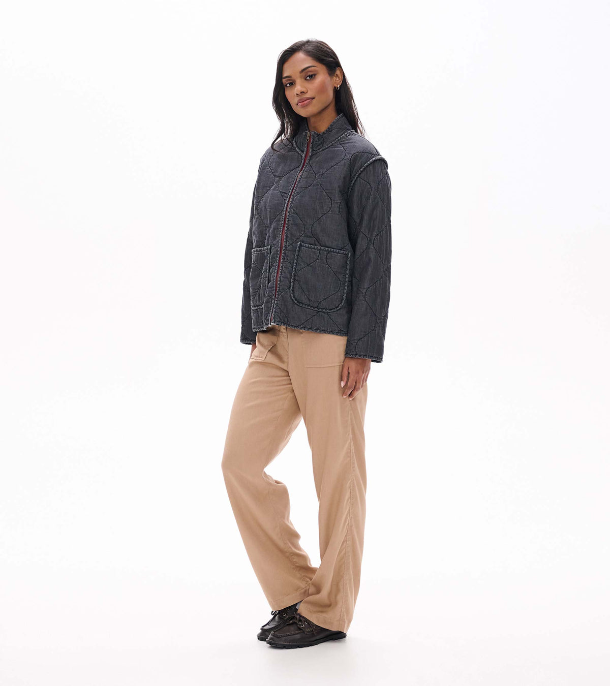 Model wearing black quilted jacket in angled front view with wavy quilting and two front patch pockets