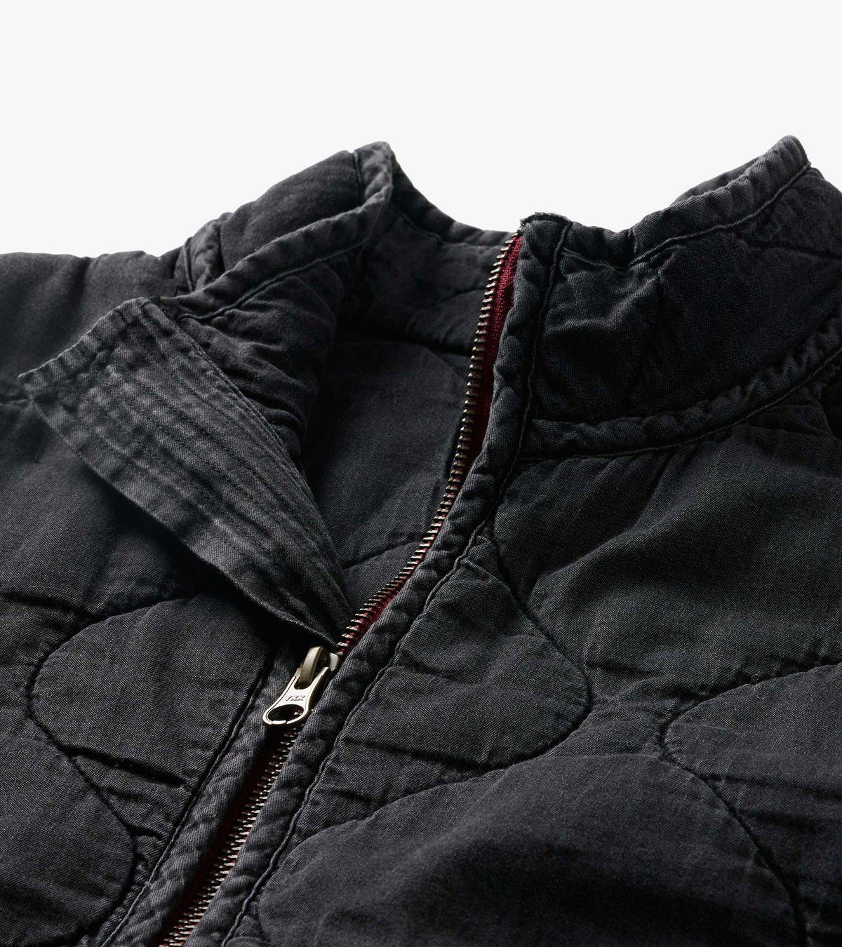 Close-up of the black quilted jacket collar and front zipper with burgundy trim