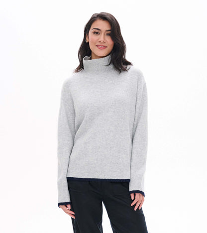 Model wearing athletic grey mock neck sweater with ribbed collar, hem, and cuffs with dark contrast trim
