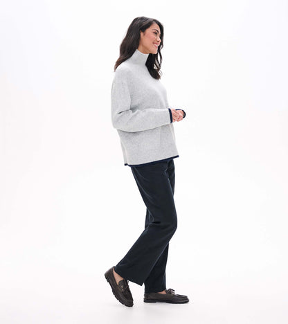Side view of athletic grey mock neck sweater with relaxed fit and dark contrast trim at hem and cuffs