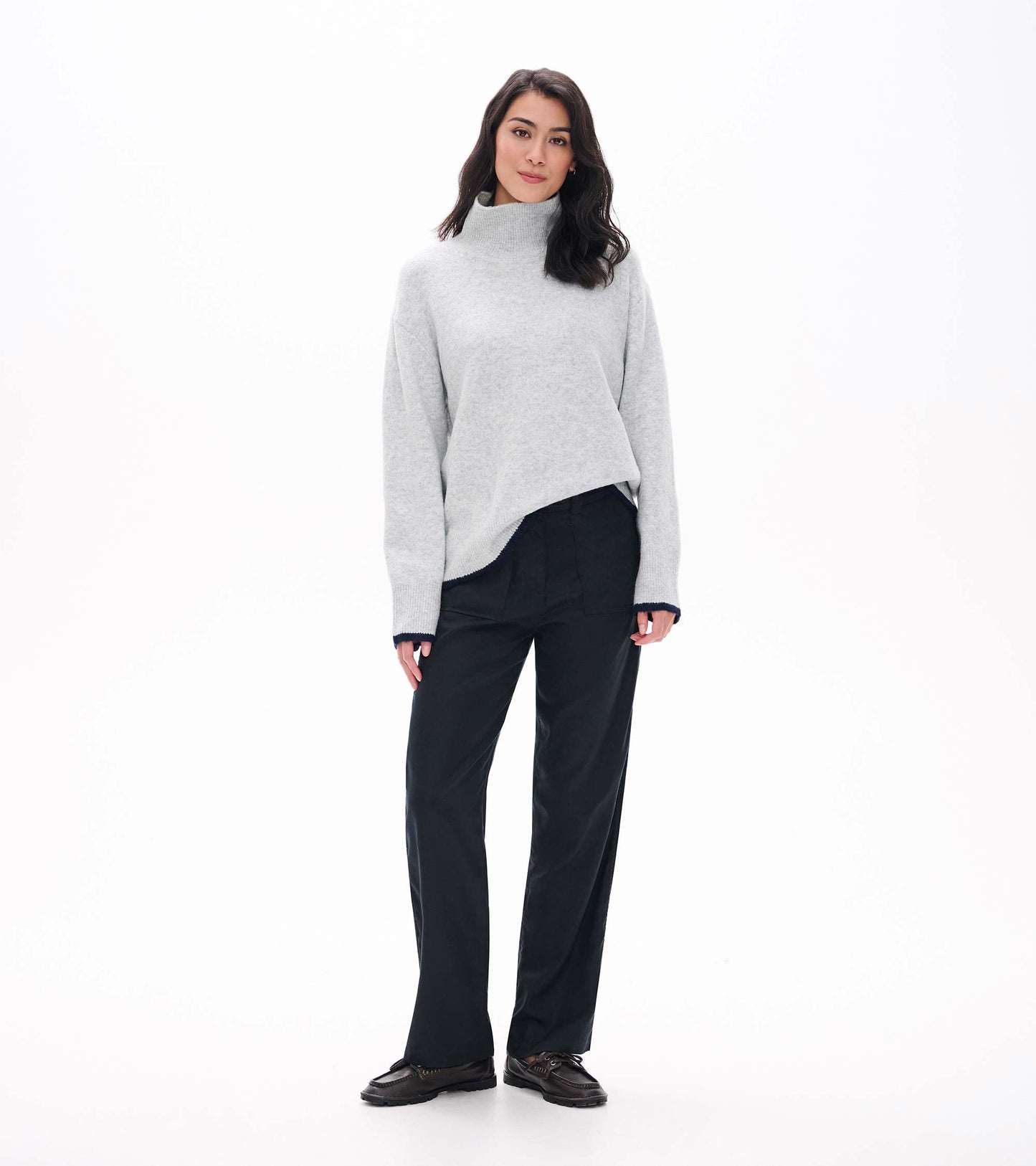Front view of athletic grey mock neck sweater styled with black pants, showing ribbed cuffs and hem
