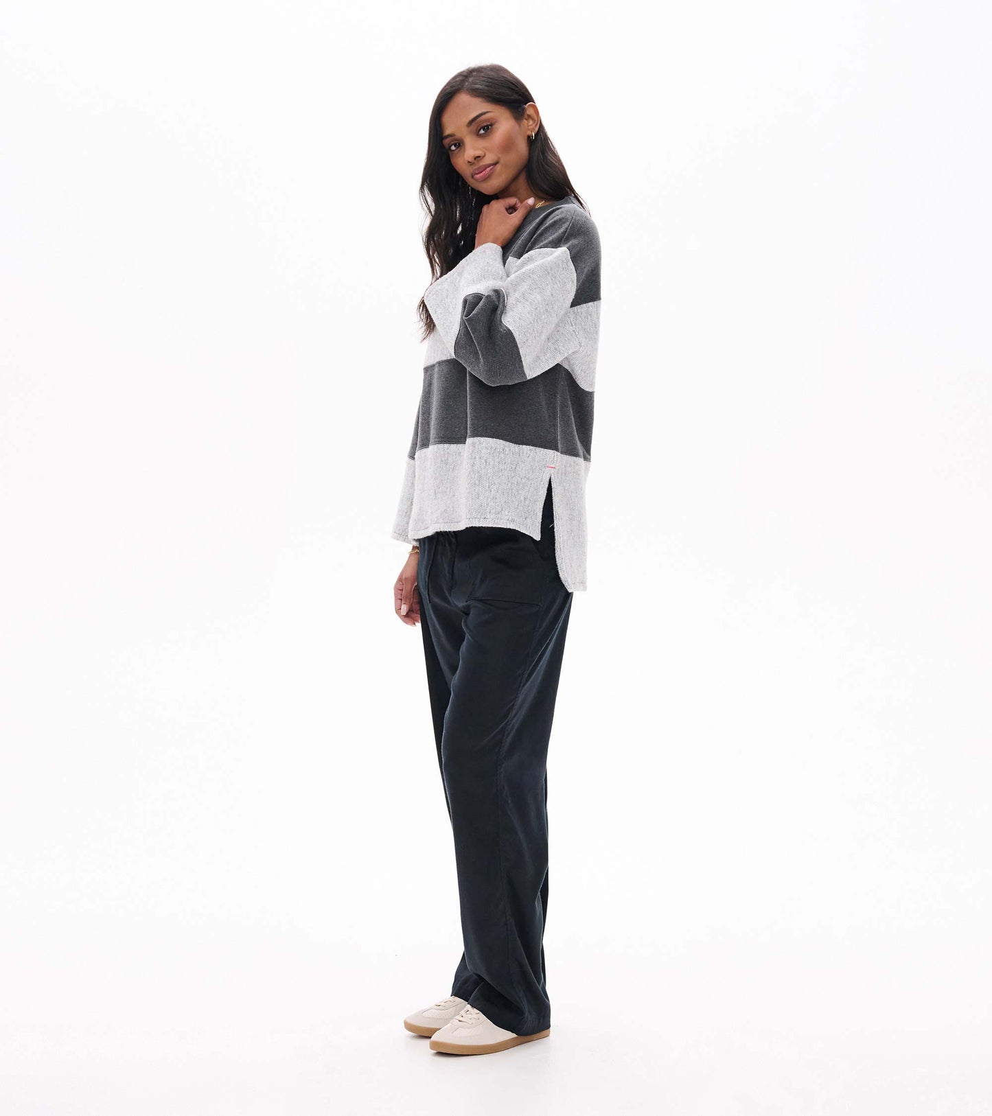 Side view of charcoal and light gray striped top with wide sleeves and a side slit hem