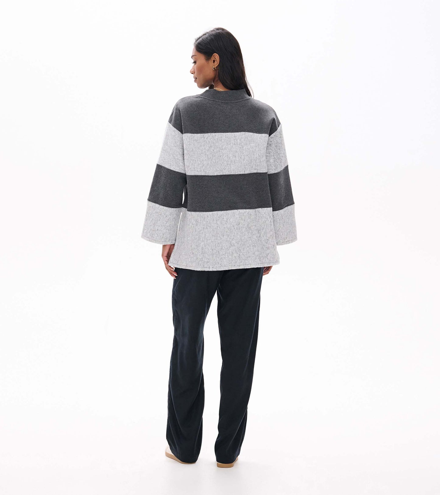 Back view of charcoal and light gray striped long sleeve top with wide sleeves and a slightly longer hem