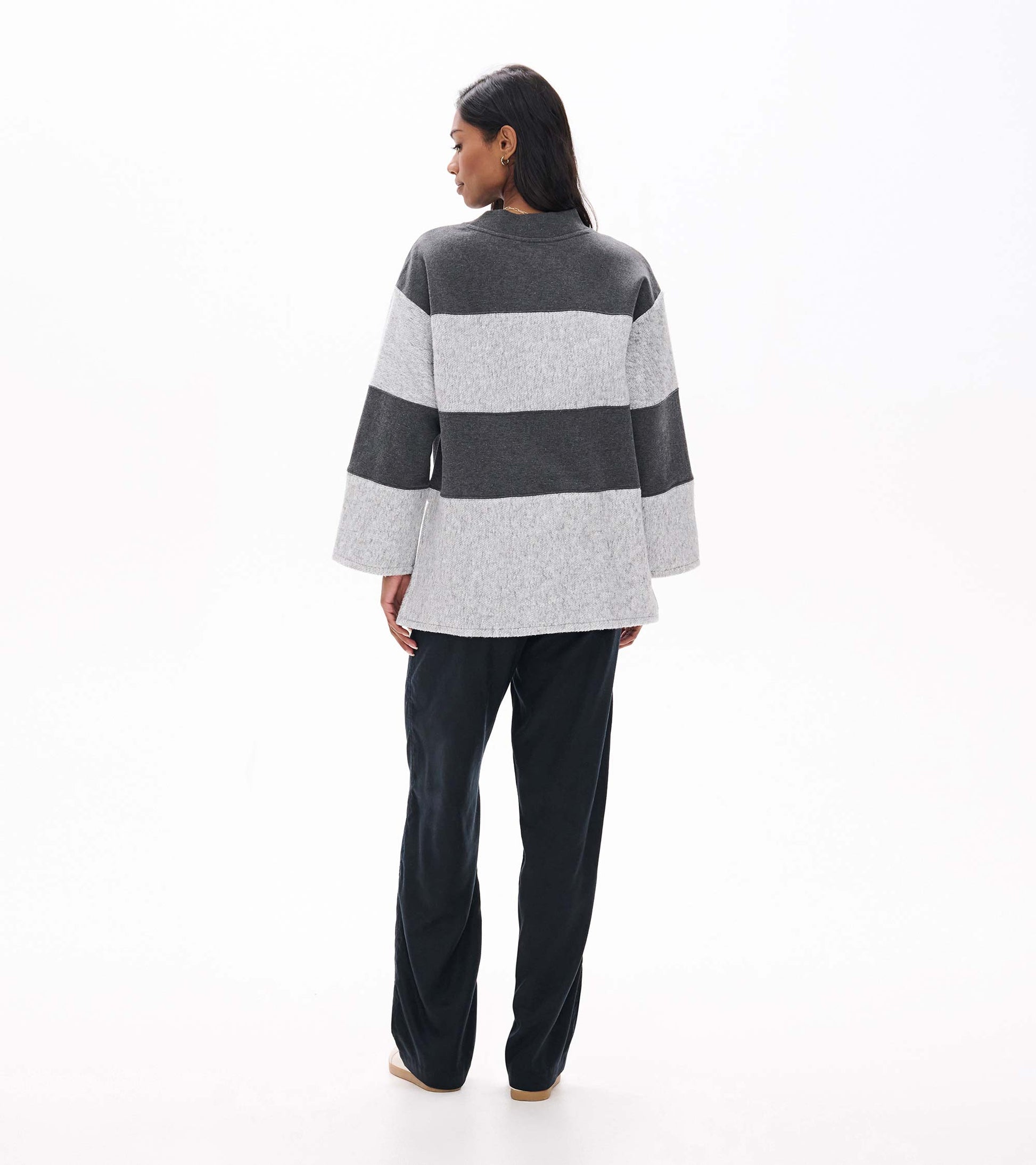 Back view of charcoal and light gray striped long sleeve top with wide sleeves and a slightly longer hem