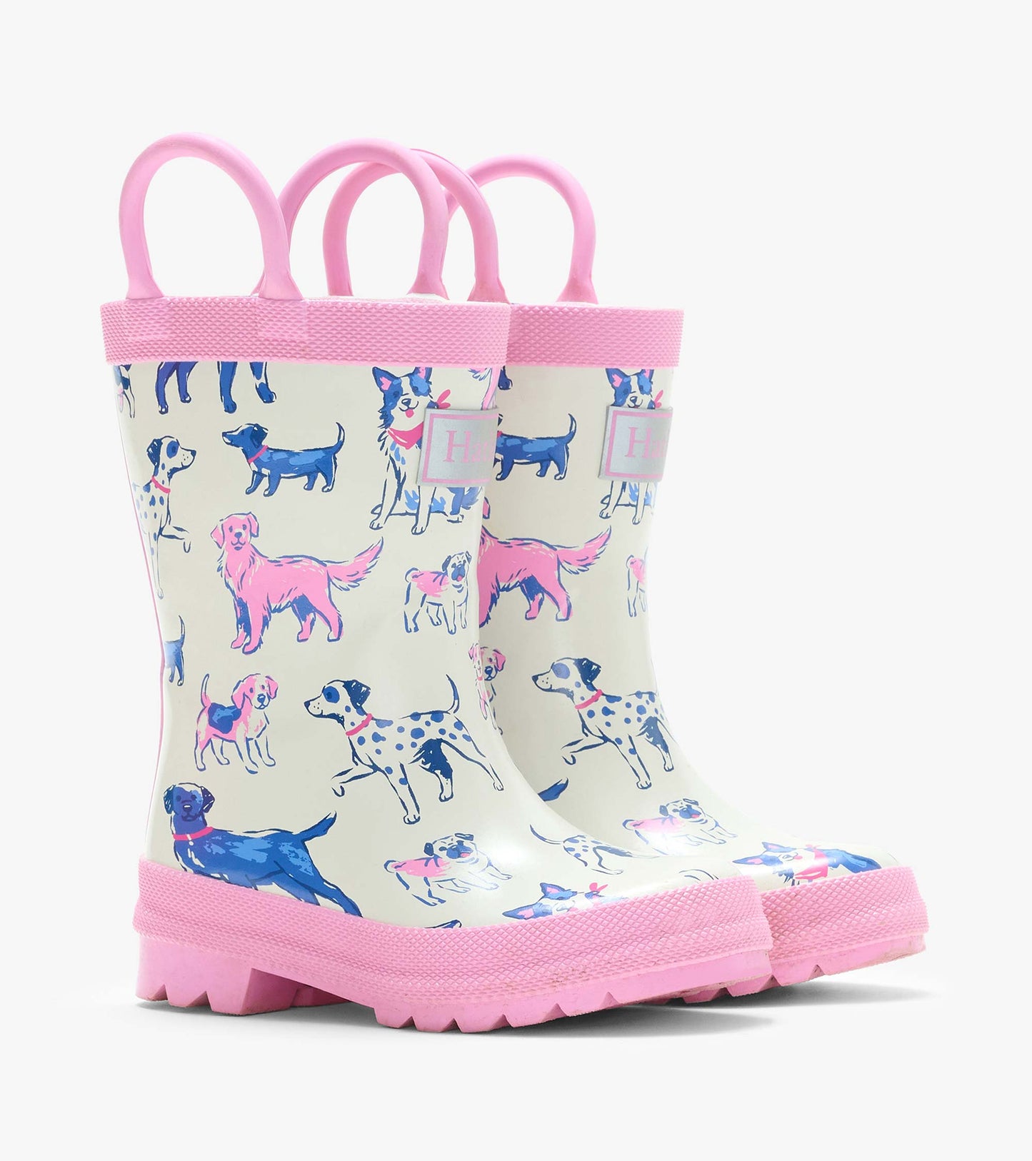 Pair of cream kids rain boots with pink handles and trim, covered in blue and pink dog illustrations