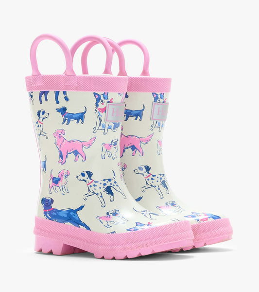 Pair of cream kids rain boots with pink handles and trim, covered in blue and pink dog illustrations