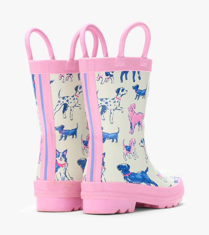 Rear angled view of cream rain boots with pink handles and trim, printed with blue and pink dogs