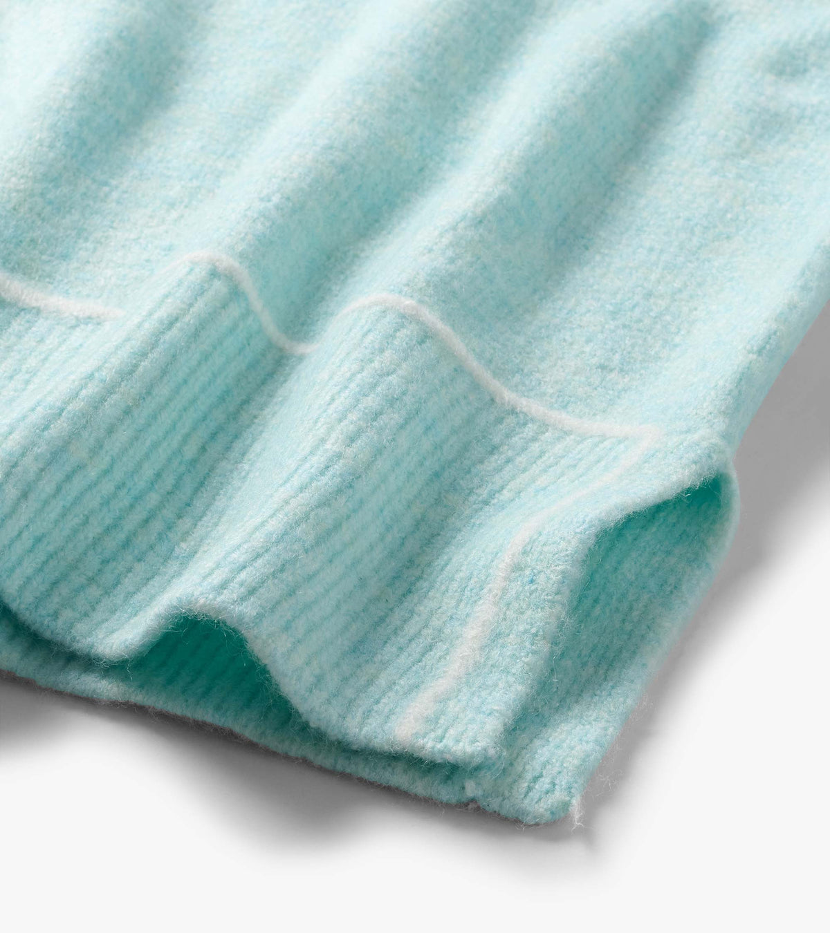 Close-up of the teal sweater hem with soft horizontal stripe detail and a ribbed edge