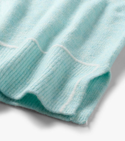 Close-up of the teal sweater hem with soft horizontal stripe detail and a ribbed edge