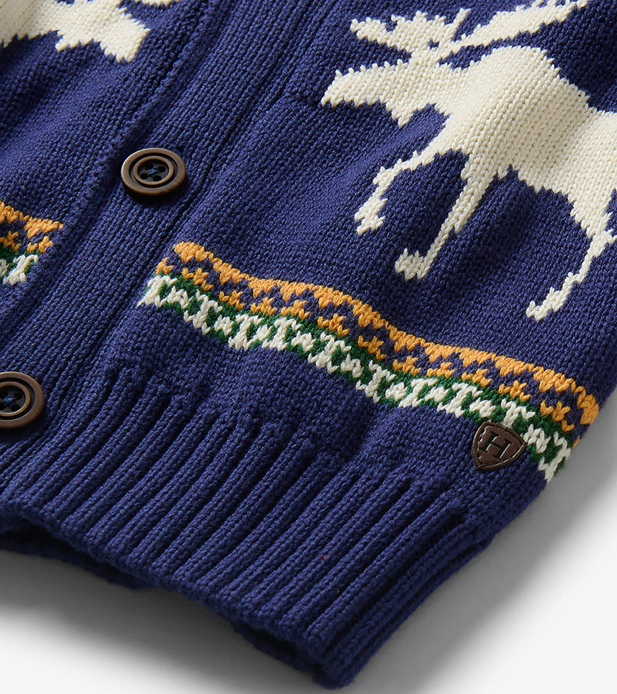 Close-up of navy knit cardigan with moose pattern, striped detail, ribbed hem, and brown buttons