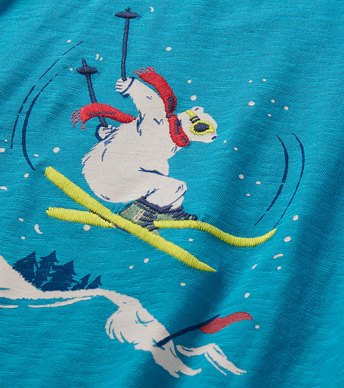 Close-up of skiing bear graphic with red scarf and yellow skis on blue T-shirt