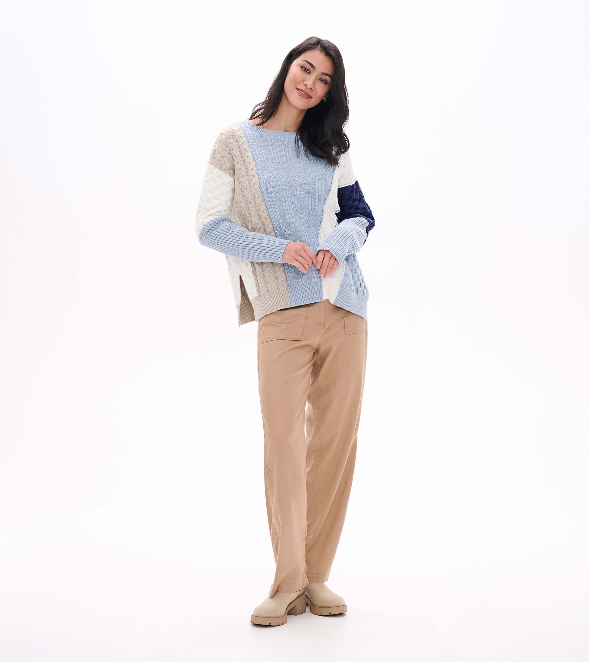 Full front view of blue mixed-pattern sweater with long ribbed sleeves and textured patchwork design