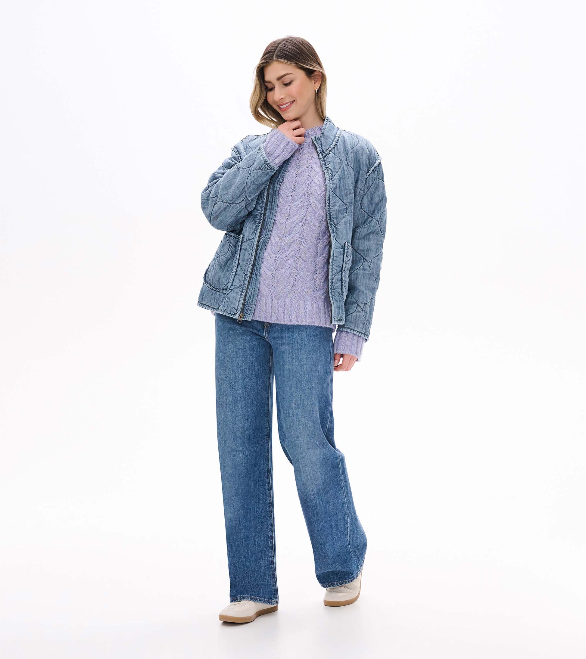 Speckle lilac cable-knit sweater styled under a faded blue quilted jacket with jeans