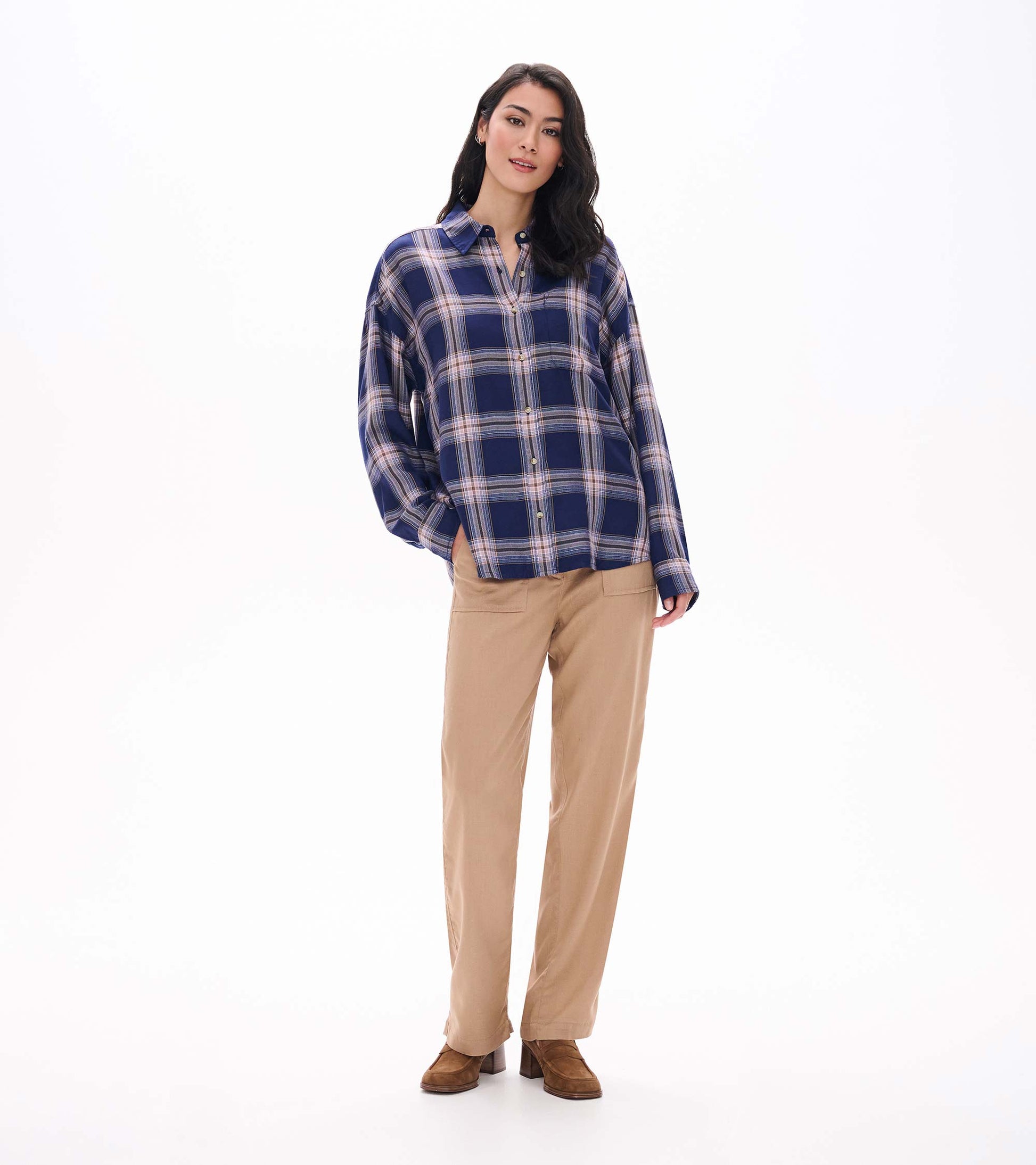 Front view of relaxed navy plaid button-down shirt with long sleeves and collar, styled with tan pants