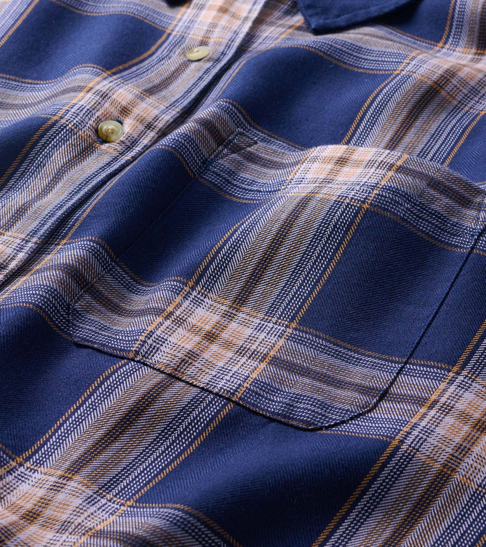 Close-up of navy plaid shirt showing chest pocket, buttons, and plaid pattern detail