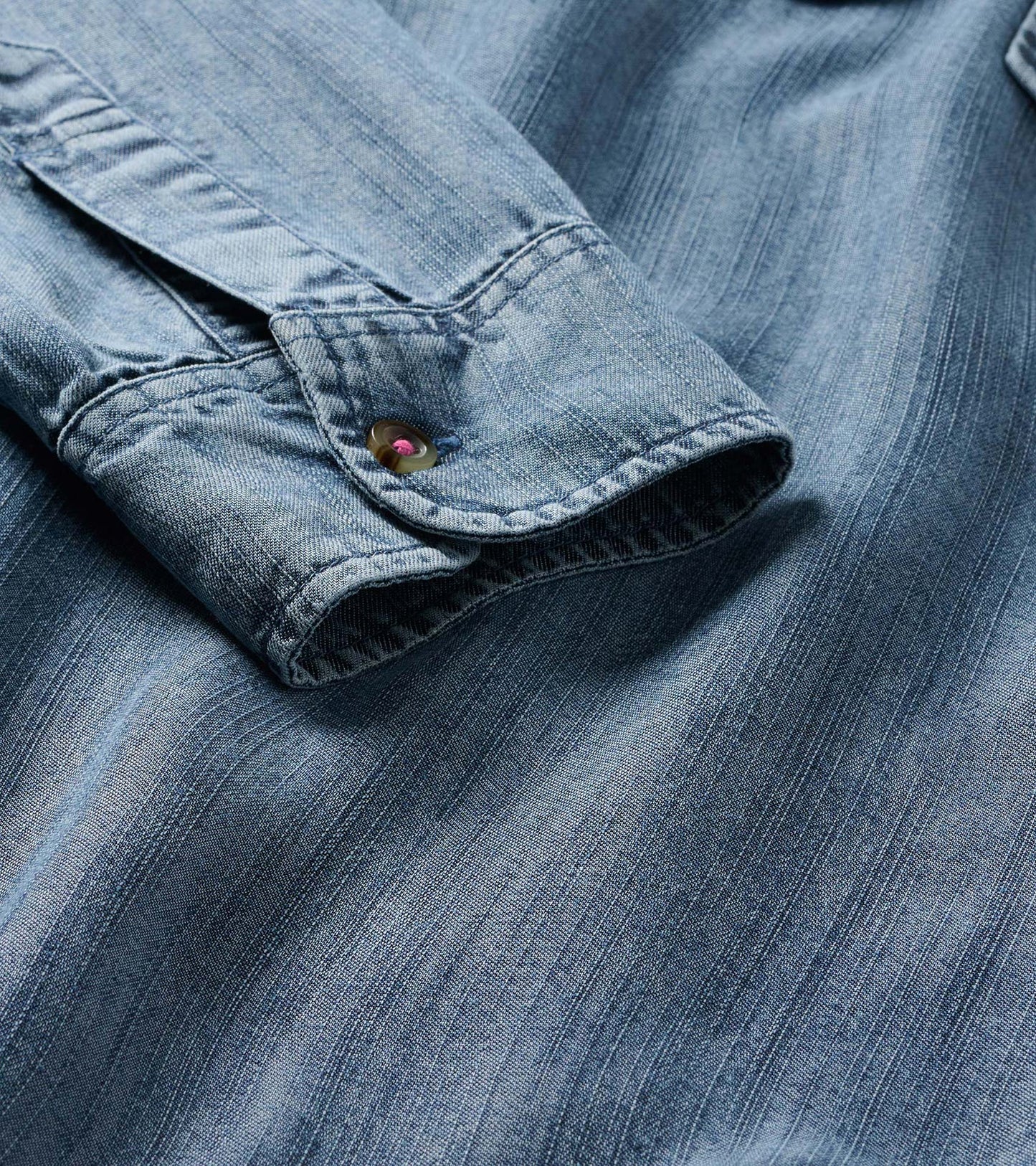 Close-up of the blue acid rinse popover dress cuff with button and subtle vertical texture