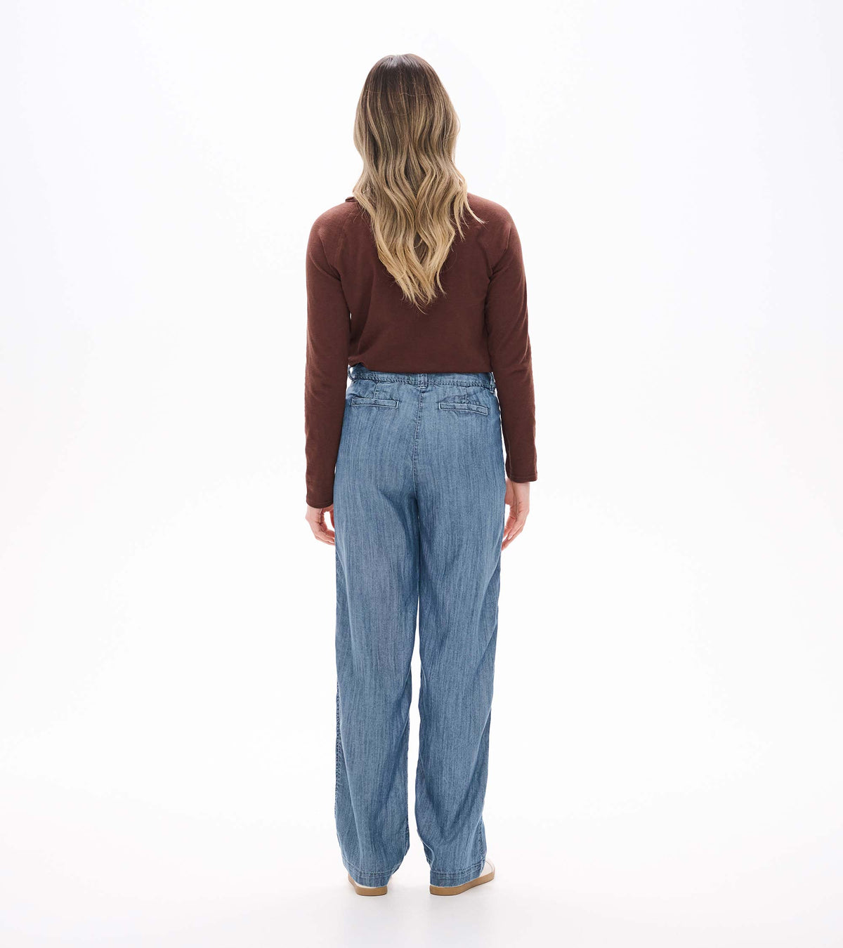 Back view of blue acid rinse wide leg pants with rear welt pockets and a relaxed full-length fit