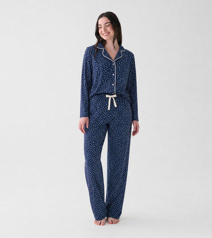 Woman wearing navy polka dot pajama set with white piping and drawstring pants, front view