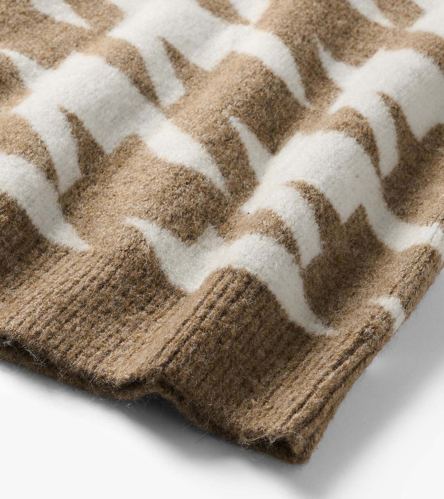 Close-up of oatmeal and white herringbone sweater knit with ribbed hem detail