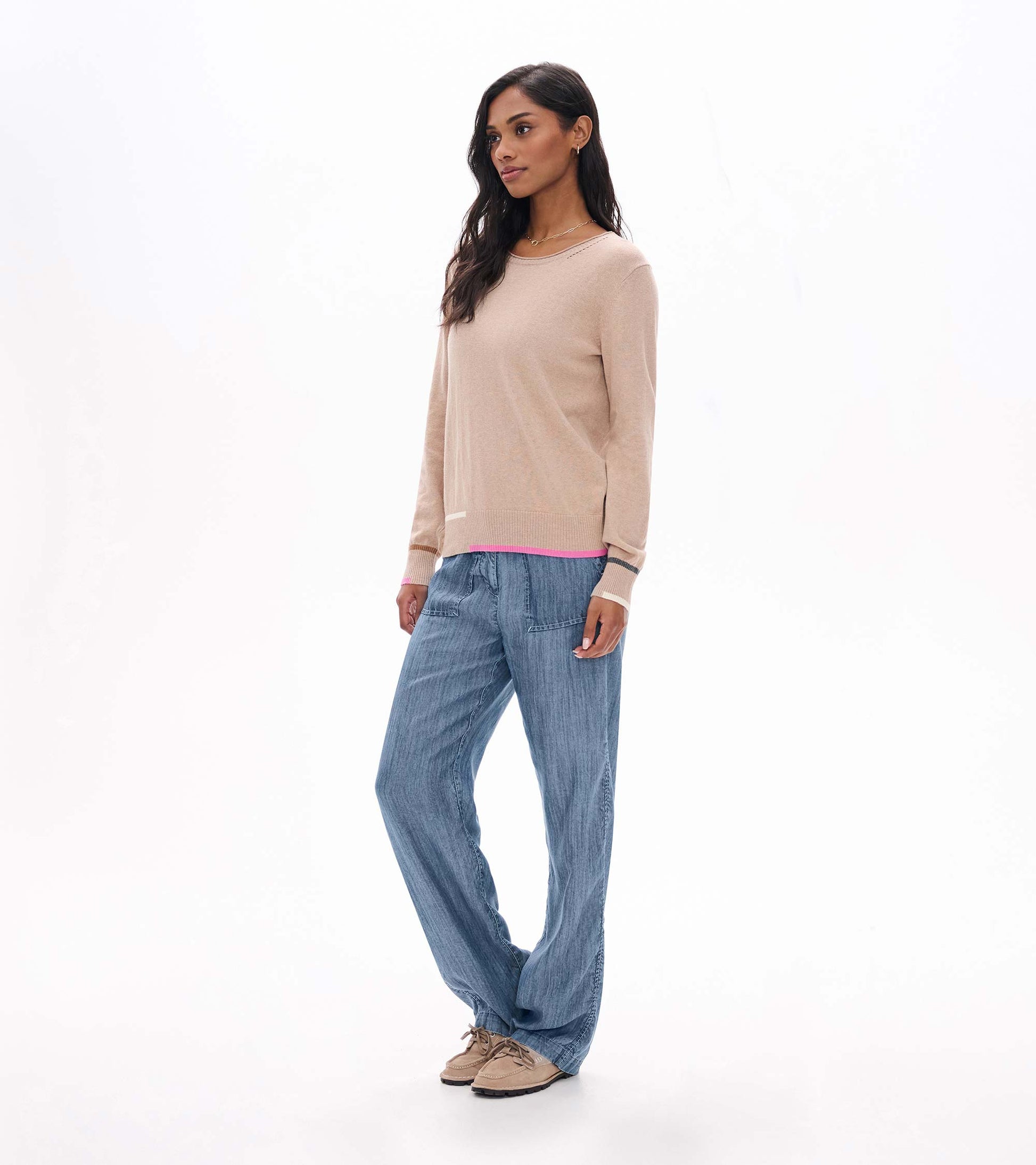 Side view of oatmeal crew neck sweater with contrast trim at hem and cuffs, styled with blue pants