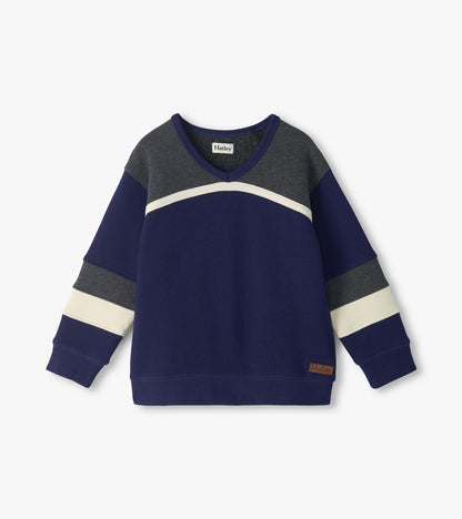 Front view of boys blue pullover top with gray yoke, curved cream stripe, and striped long sleeves