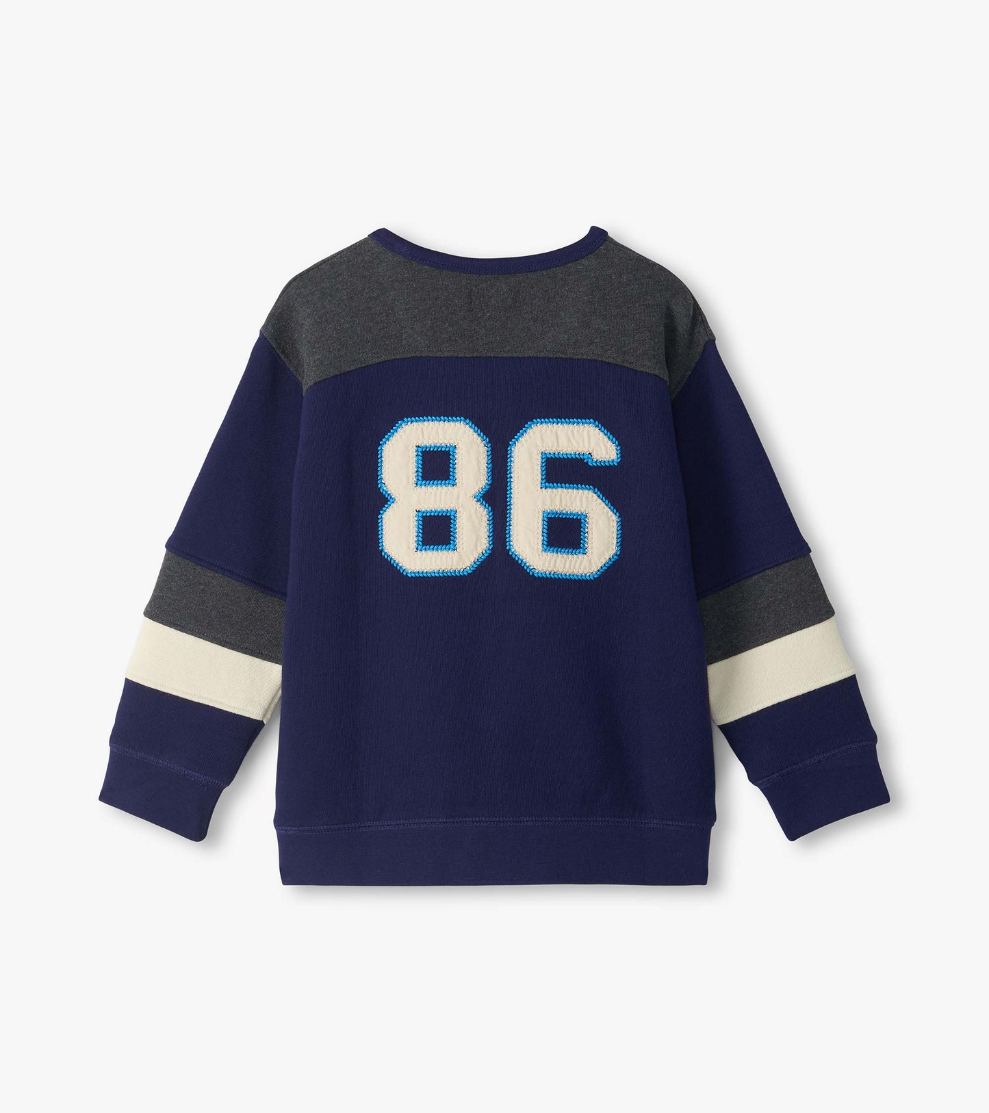 Back view of boys blue pullover top with gray yoke, cream sleeve stripes, and large 86 applique