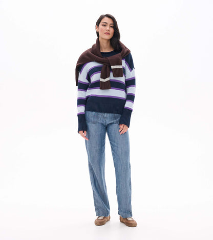 Front view of striped rolled collar sweater styled with another sweater draped over the shoulders