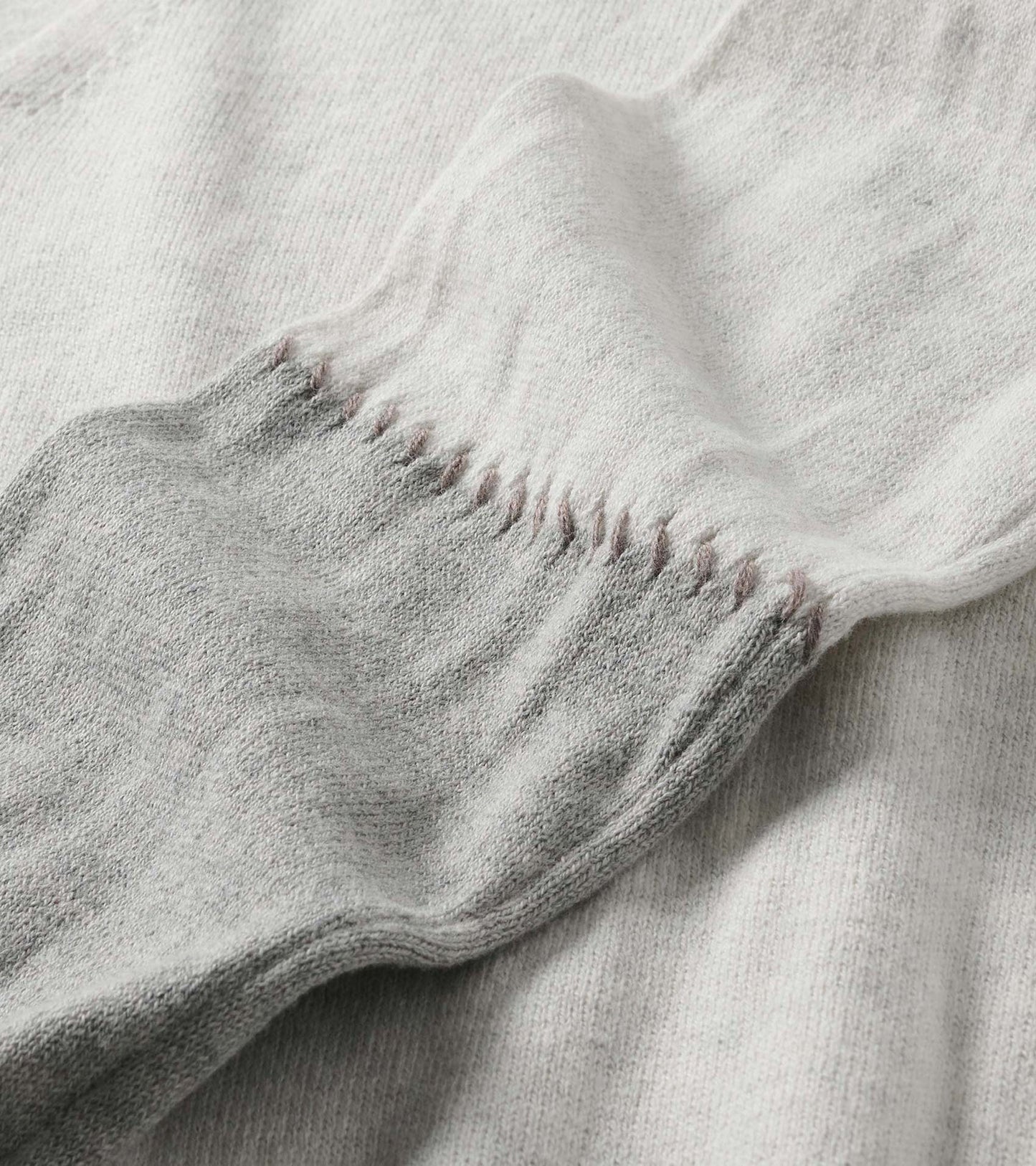 Close-up of the pale grey melange sweater dress cuff with stitched detail along the sleeve seam