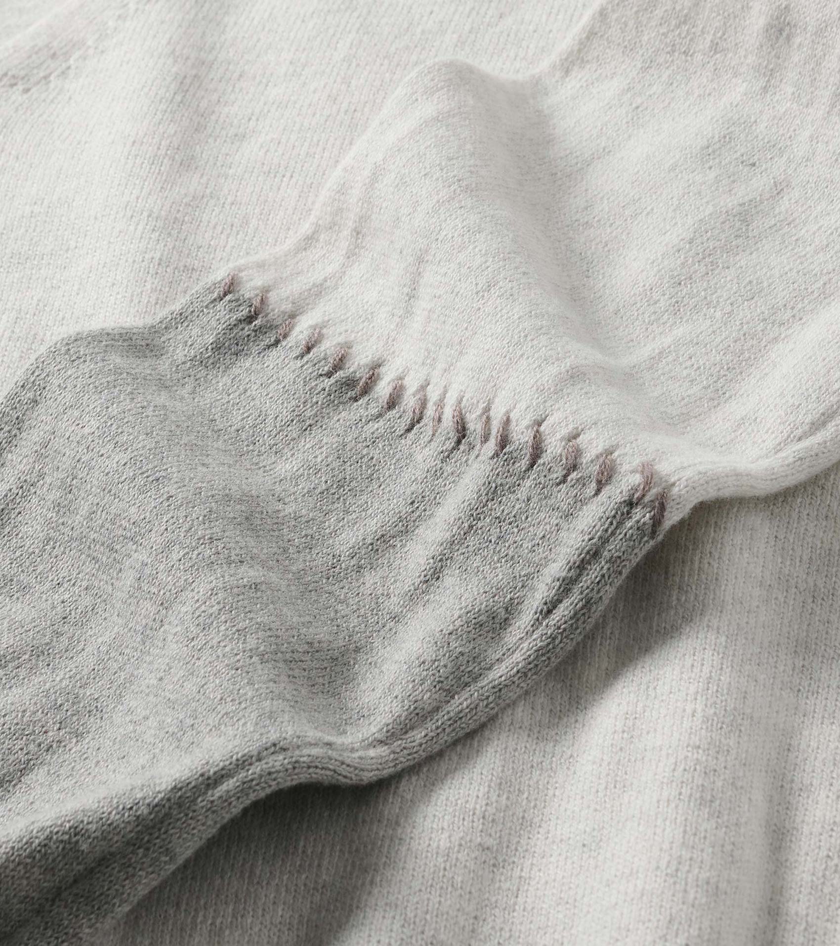 Close-up of the pale grey melange sweater dress cuff with stitched detail along the sleeve seam