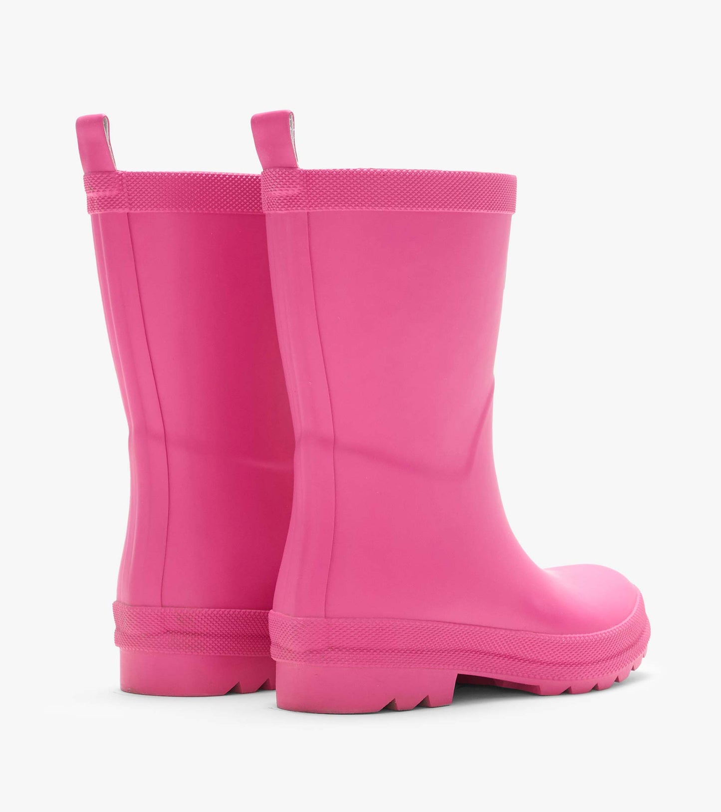 Pair of pink matte rain boots from the back side with pull tabs, textured trim, and lug soles