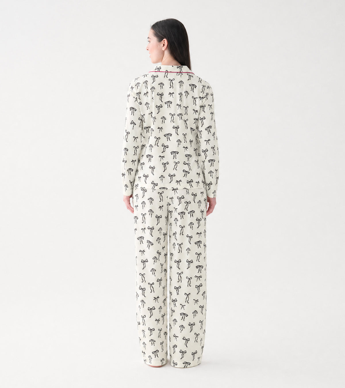 Back view of cream pajama set with black bow print and pink piping across the collar