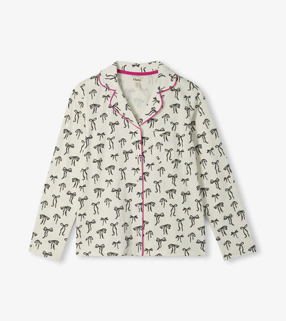 Cream pajama top with black bow print, pink piping, button front, and chest pocket