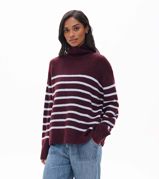 Model wearing a rumba red mock neck sweater with white horizontal stripes, front view
