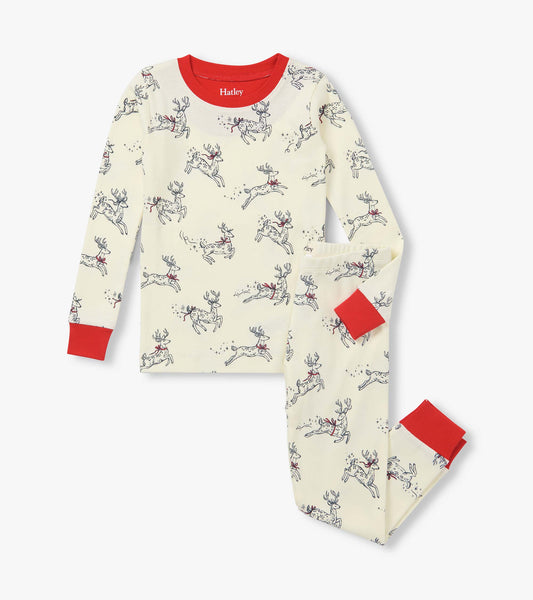 Girls two-piece pajama set in cream with leaping reindeer print and bright red neckline and cuffs