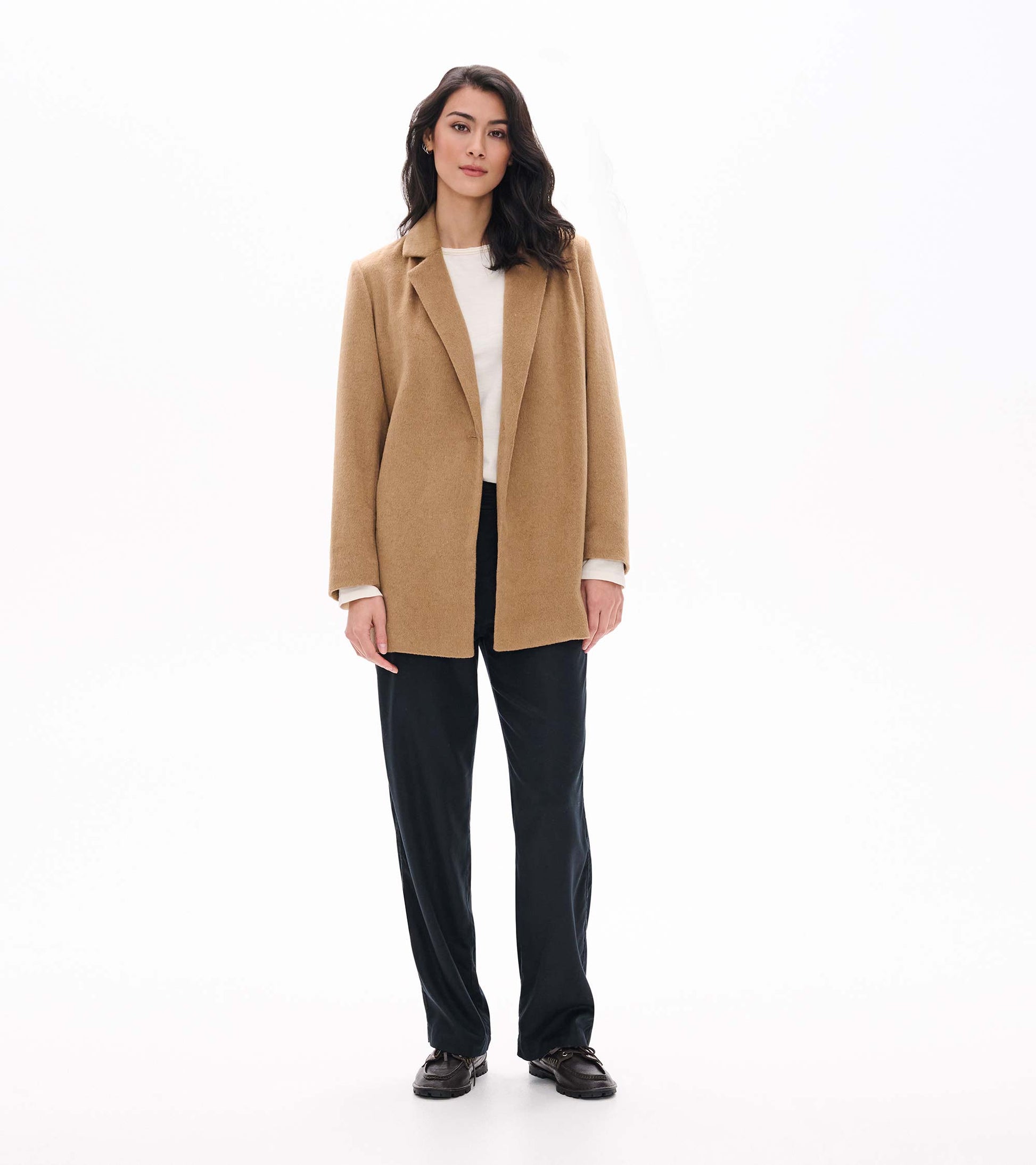 Model wearing camel open jacket, full-length front view over white top and black pants