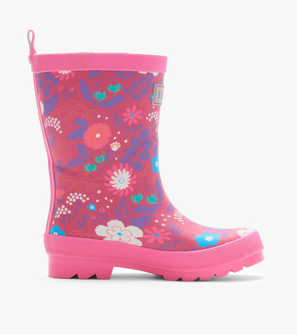 Side view of a pink kids rain boot with tiny flower print, textured trim, pull tab, and treaded sole