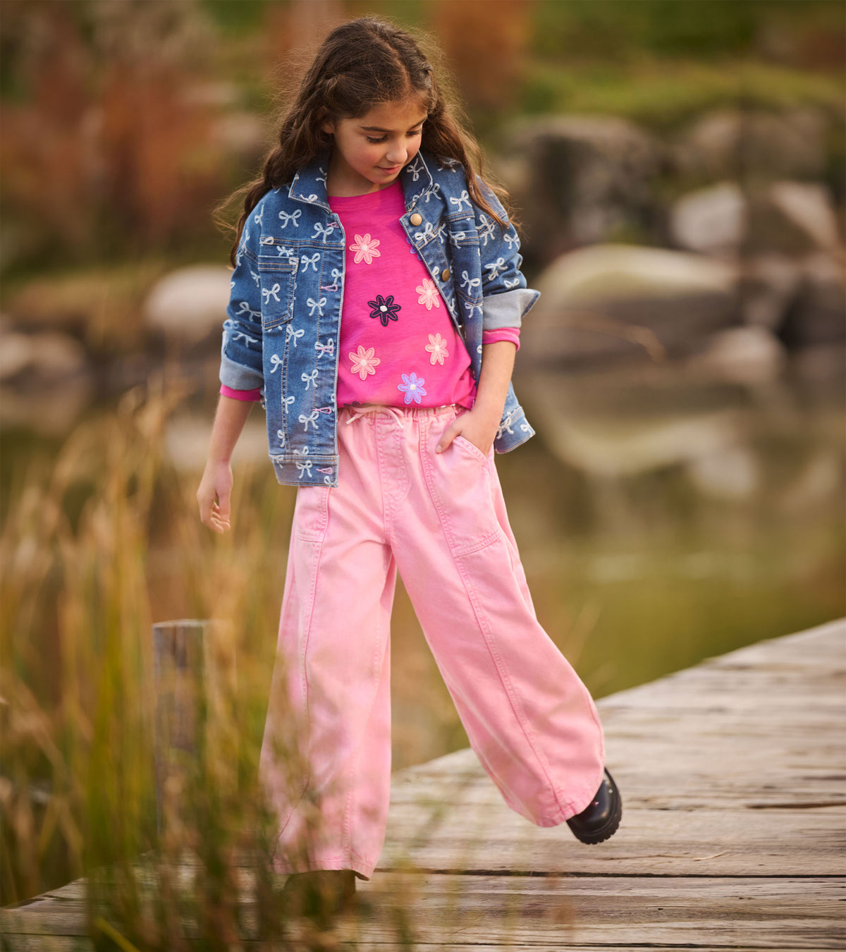 Girl wearing a berry-pink flower graphic T-shirt under a blue bow-print jacket
