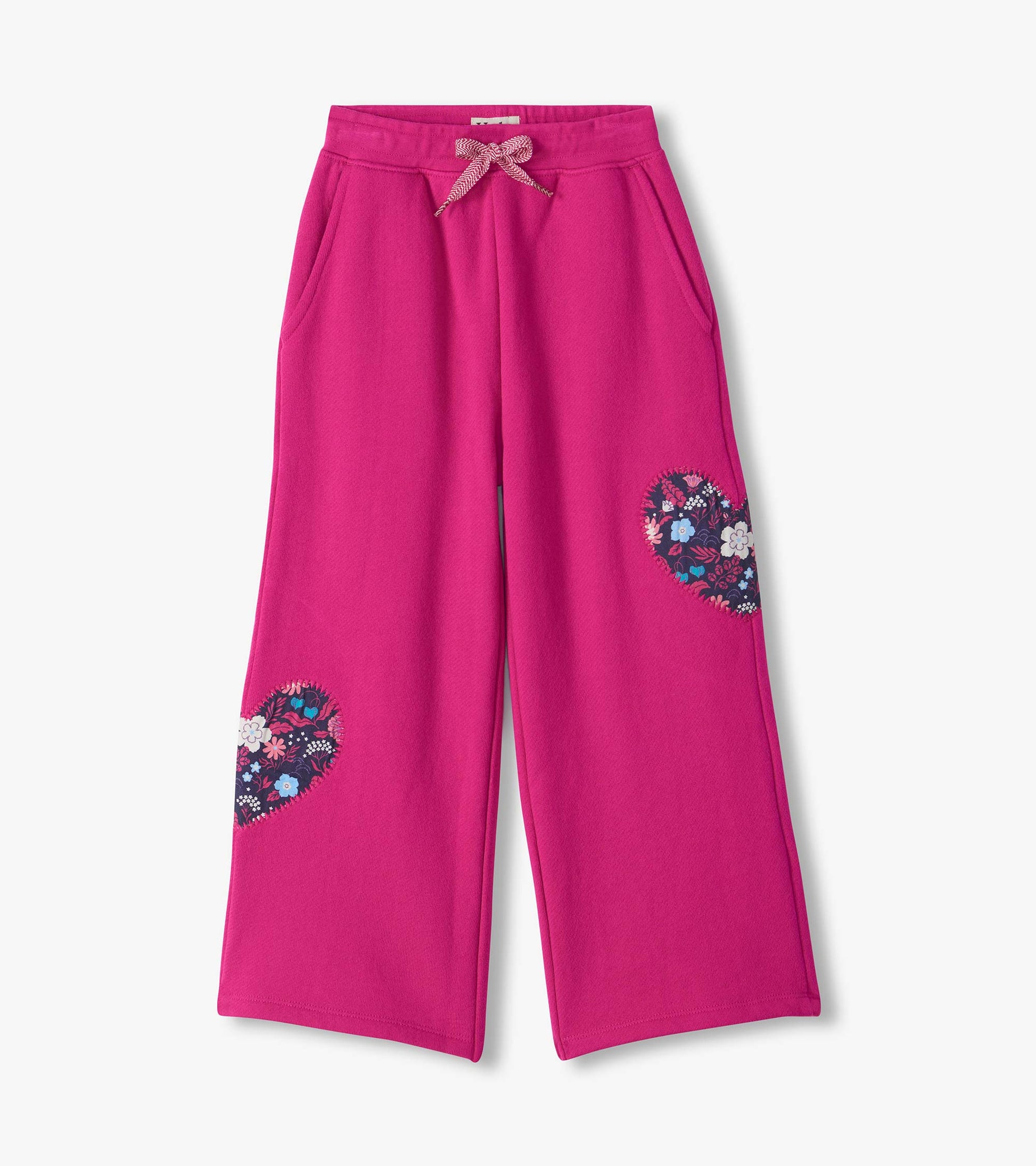 Bright pink wide leg track pants with side pockets, drawstring waist, and floral heart patches on the legs